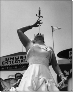 Женщина цирка выполняет трюк глотания  меча